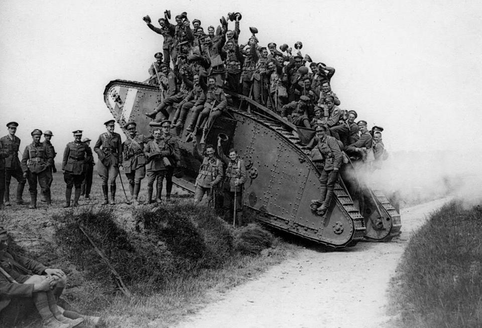 nintchdbpict000303439982 A black and white image of a First World War Tank going up a bank with soldiers in uniform on top of the tank and stood by it leaning on it, posing for a photograph.