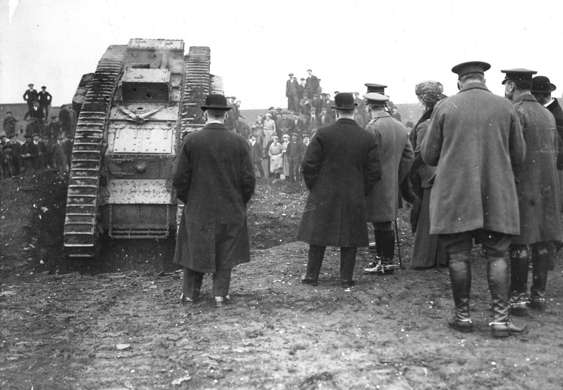P_Mark V female_King Geirge V & William Tritton Fosters__7506-025 A black and white photo taken from behind of a First World War Tank with people stood beside and in front looking at the tank.