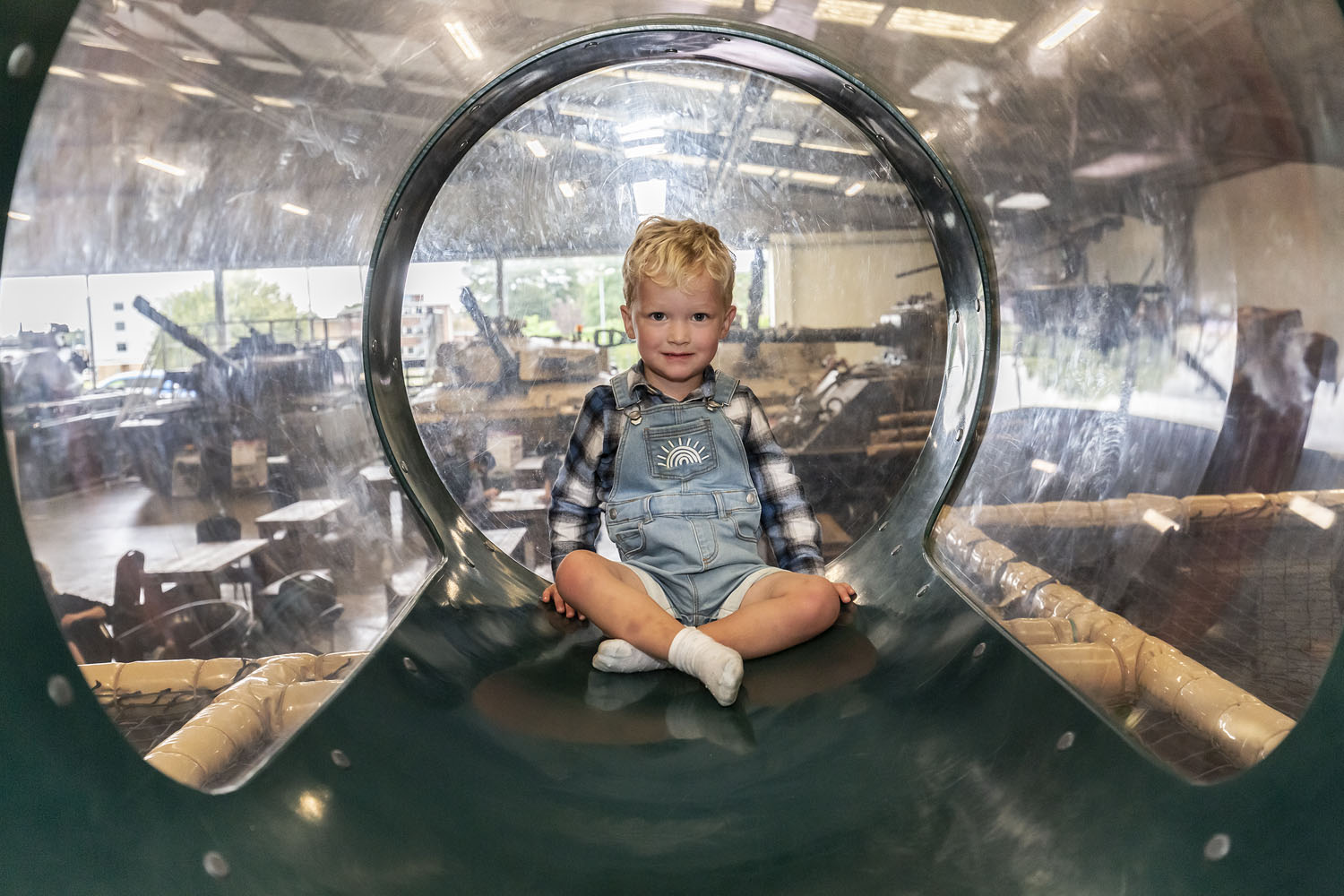A colour image of a child in a soft play area with tanks behind them.