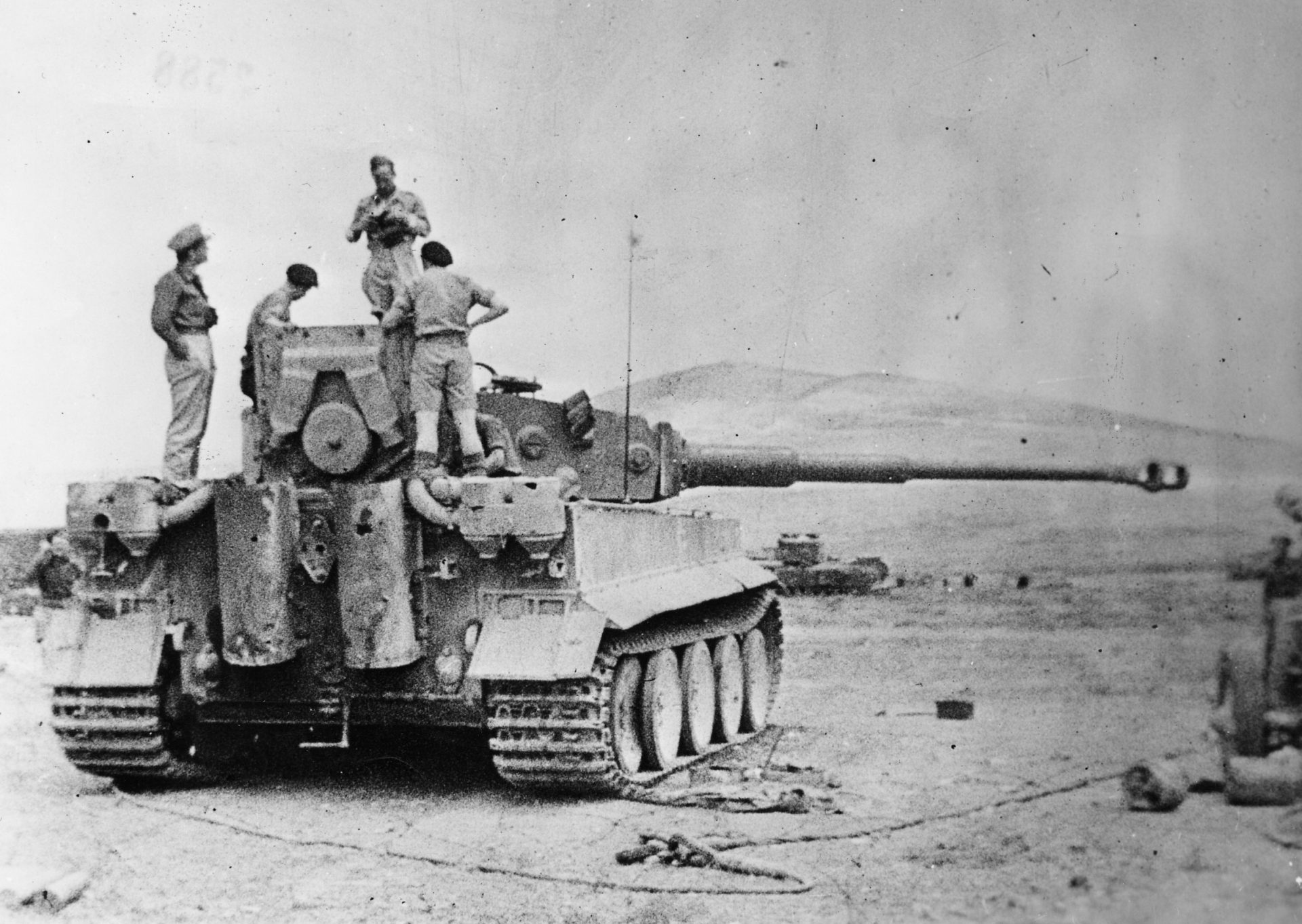 Tiger 131 is recovered from the battlefIeld A black and white photo of Tiger 131 with troops stood on the back and top of it.