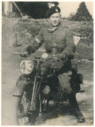 vaux full sized A vintage photo showing a young male solider on military style motorbike, dressed in uniform with googles around their neck. The number 43 covers the front light.