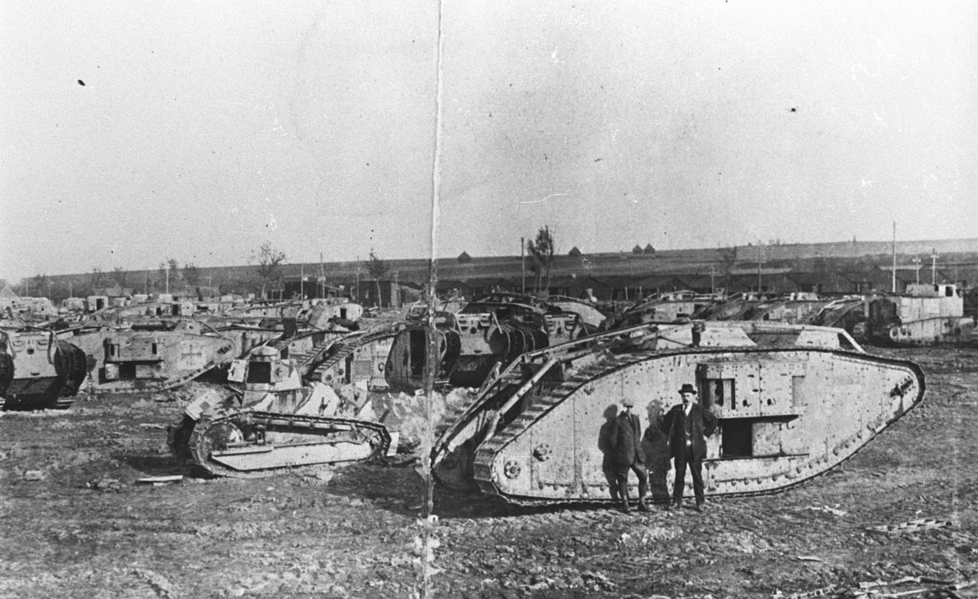 1546-E6 Tank Corps workshops Black and white photograph of WWI tanks in a field, with two men standing in front of them.