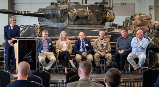 290x528 Full colour, interior shot of 7 speakers sat on a stage in front of the sherman fury tank.