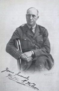 Walter Wilson Black and white photograph of a middle aged man in uniform posed on a chair, with a signature bottom left.