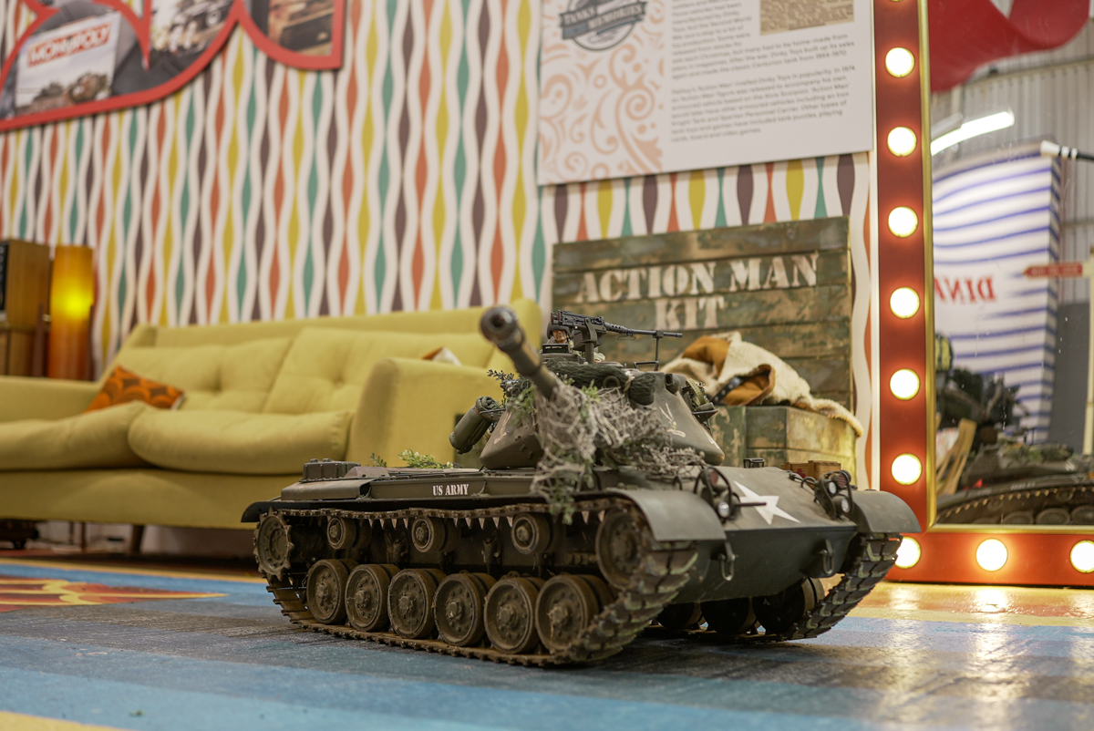The auctioned M47 remote control scale model Small model tank maned by an action figure. The tank is military green with 'US ARMY' printed on the side in white, and a white star at the front.