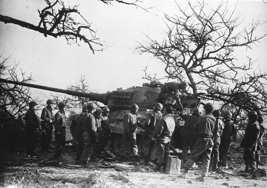 American soldiers inspect an abandoned Tiger II Black and white photo of soldiers stood around a tank.