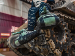Sherman Fury Tank Slippers Tank-themed slippers, modelled by person sat on top of tank.