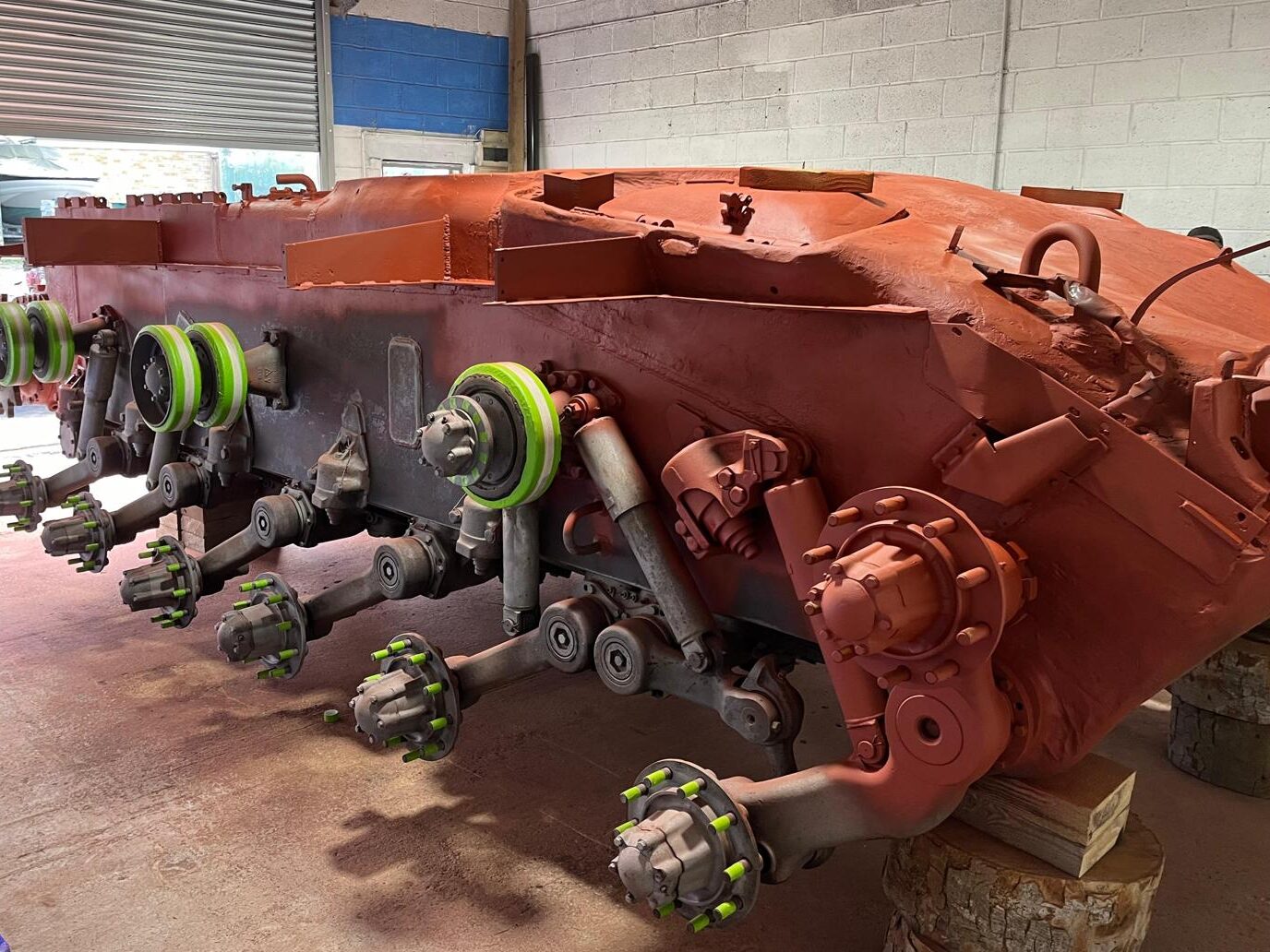 The next step in Pyle’s workshop is reconditioning the wheel bearings Photo of stripped-back tank in workshop, freshly painted red, with wheels removed.