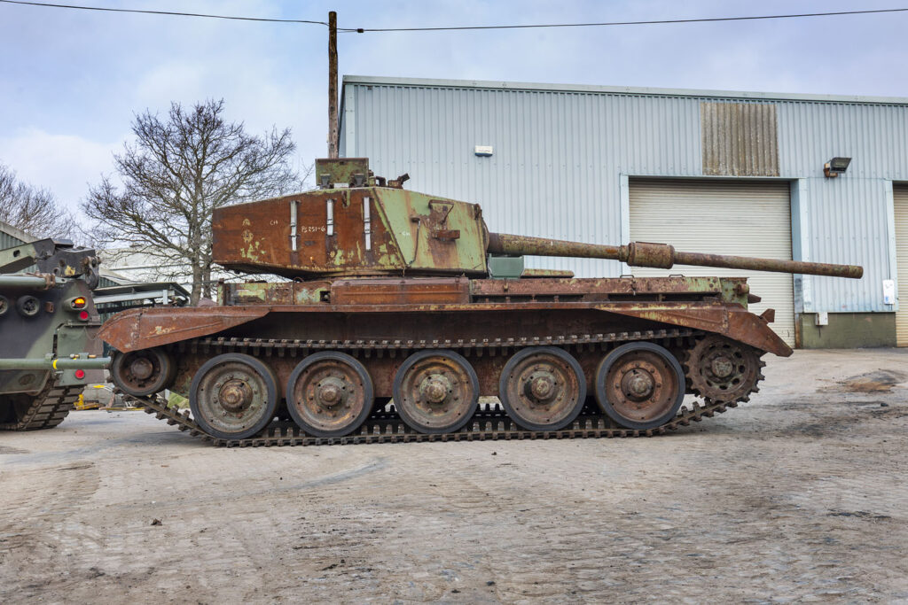 Charioteer Arrival_023 Photo of a rusty/red coloured tank outside a workshop building.