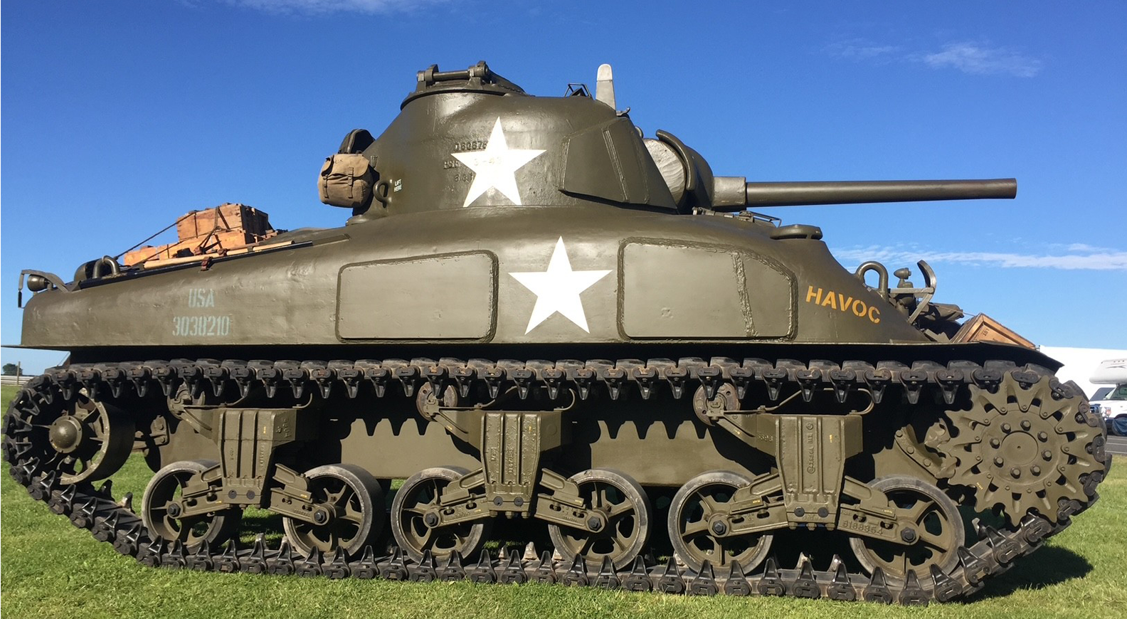 Sherman Green tank with four crew members, with a grandstand in the background.