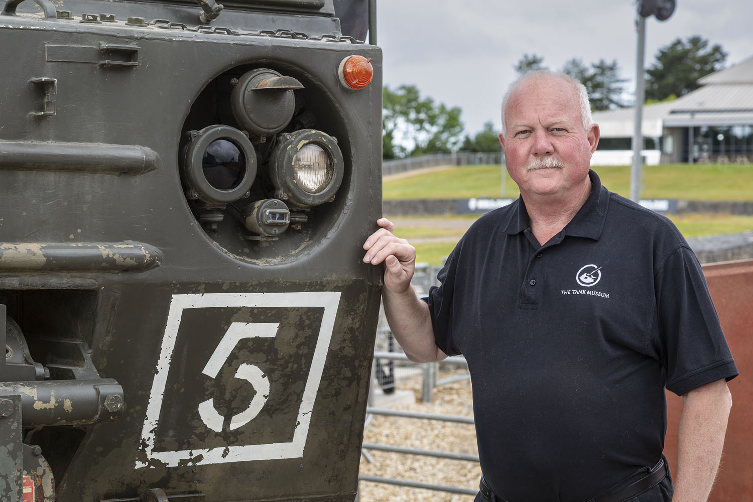 Workshop Manager Duncan Masters Man with white hair and moustache with his hand on a vehicle.